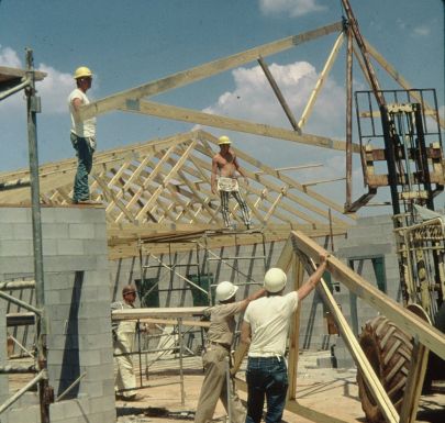 Wooden trusses being installed on concrete block walls.