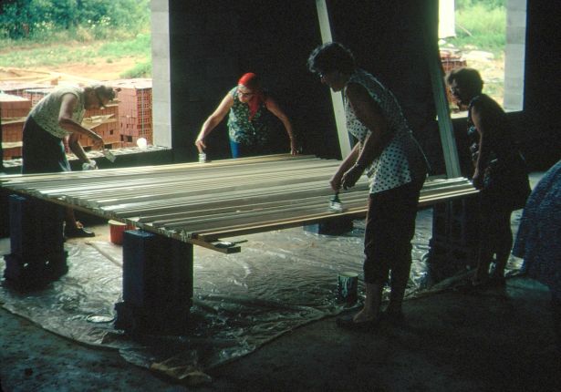 Women painting wooden window frames.