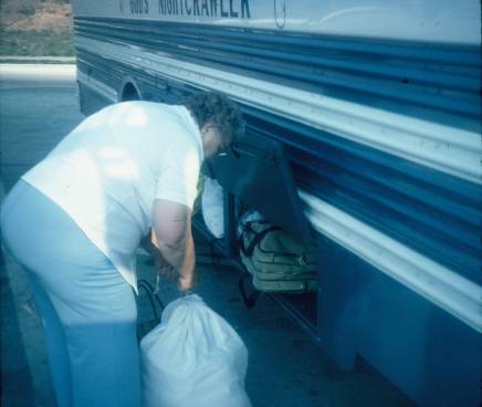 Woman loading baggage into God's Nightcrawler, an overnight church bus.