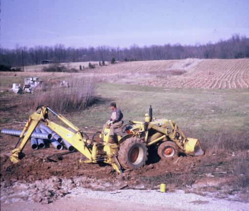 Backhoe excavating for drainage tiles.