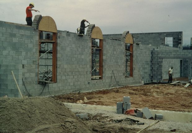 Men laying concrete blocks over arched windows.