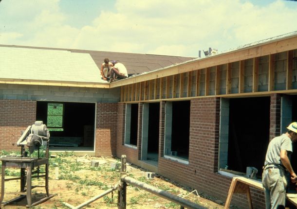 Men laying brick and installing roofing on a church.