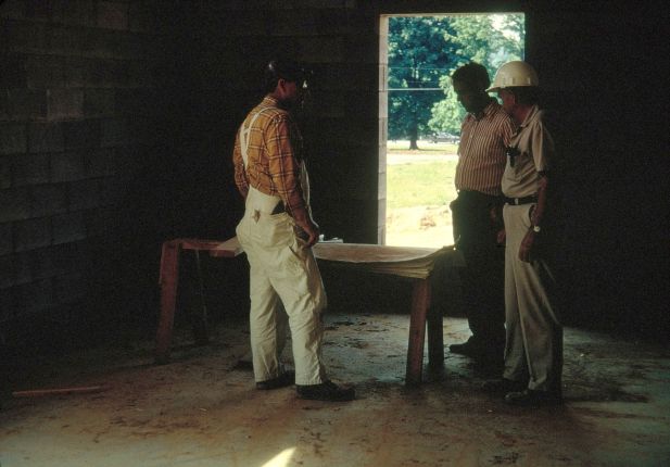 Men examining plans inside a building under construction.