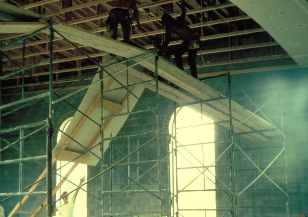 Man installing drywall on a high ceiling.