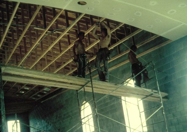 Man installing drywall on a high ceiling.
