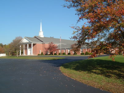 Church and autumn tree with colored leaves.  Parking lot and covered entrance to the Paoli United Methodist Church.
