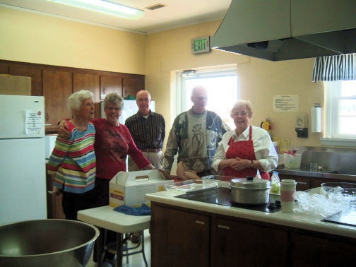 Members clean up in the kitchen after a dinner for a member's funeral.